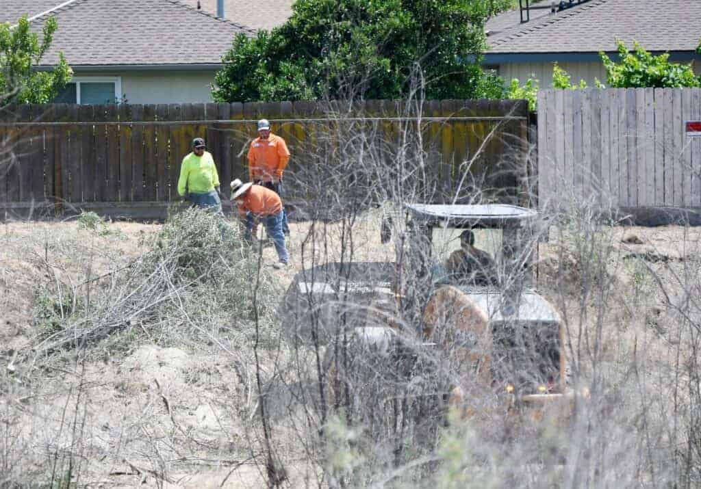 Photo - Workers clean up the river bottom after a fire destroyed two homes last week.