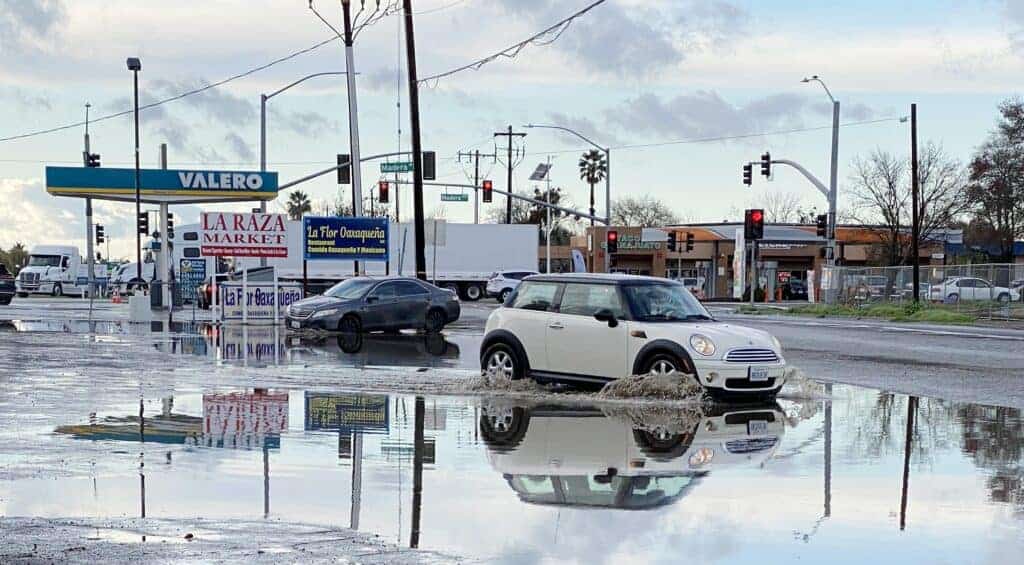 Photo - Motorists travel through a flooded parking lot near the corner of Madera and Pecan Avenues shortly after the rain storm on Tuesday.