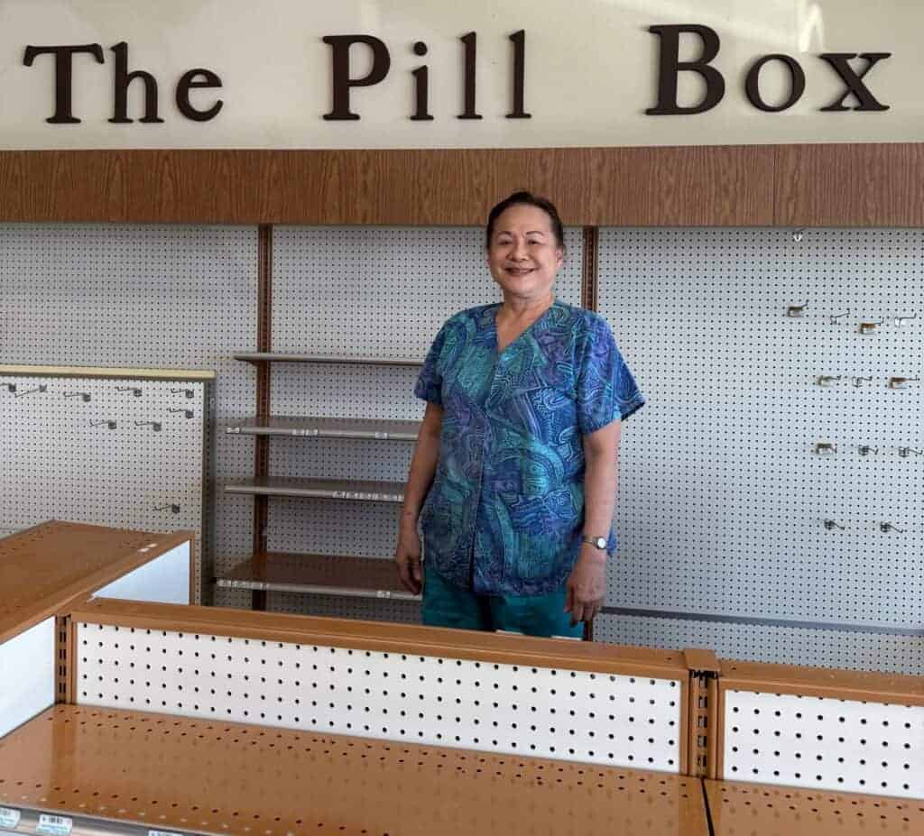 Photo - Pill Box Pharmacy owner Debra Chu-Yep stands in front of empty shelves as she closed the store on July 30, after 44 years in business.