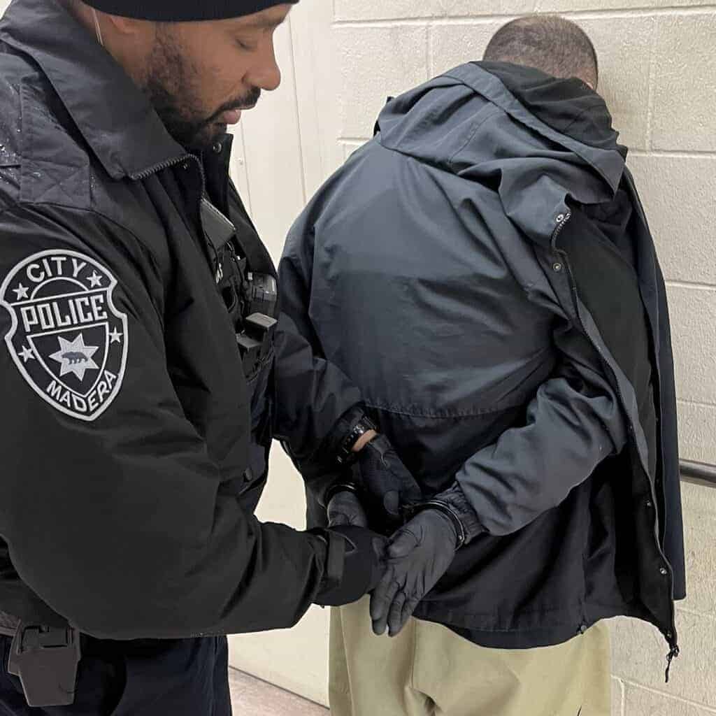 Photo - Madera Police Officer Phillip Thomas puts the handcuffs on Kyle Cevasco, who was found to be wearing body armor and a concealed gun Saturday night.