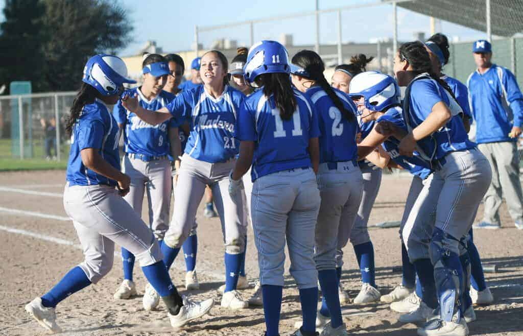 Photo - Members of the Madera Coyotes softball team greet Sofia Perez, left, as she heads to the plate after hitting a grand slam in a 6-1 victory over the Madera South Stallions on Friday.
