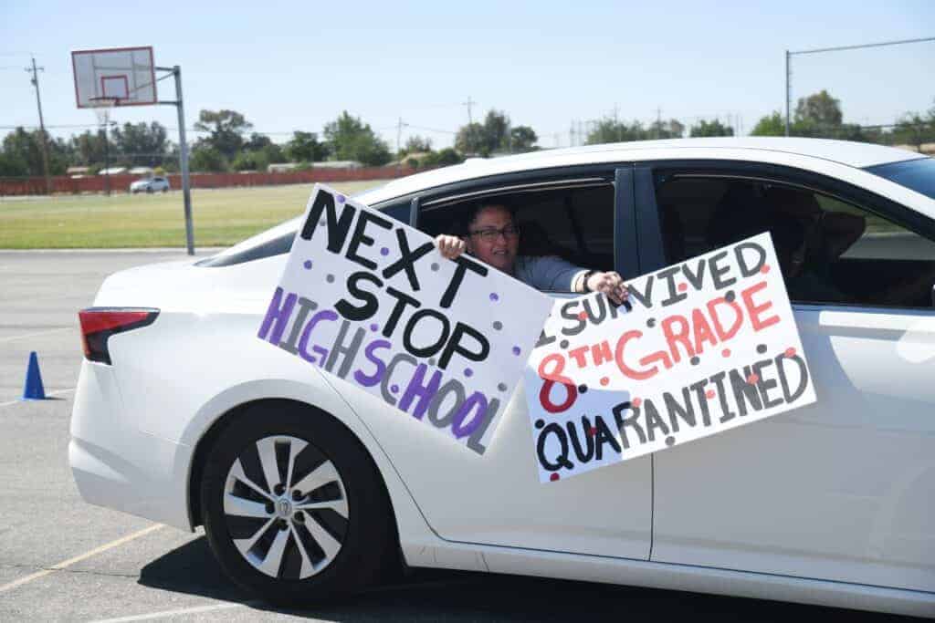Photo - A student promoting from Desmond Middle School displays a clever sign during a drive-thru ceremony on June 11.