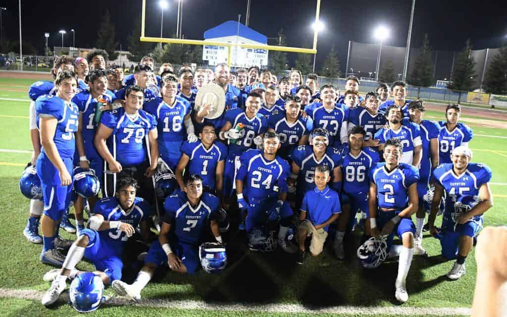 Photo - Madera Coyotes football head coach Kenny Paolinelli stands with the Governor’s Hat and his team after a 28-14 victory over the Merced Bears in the annual rivalry game.