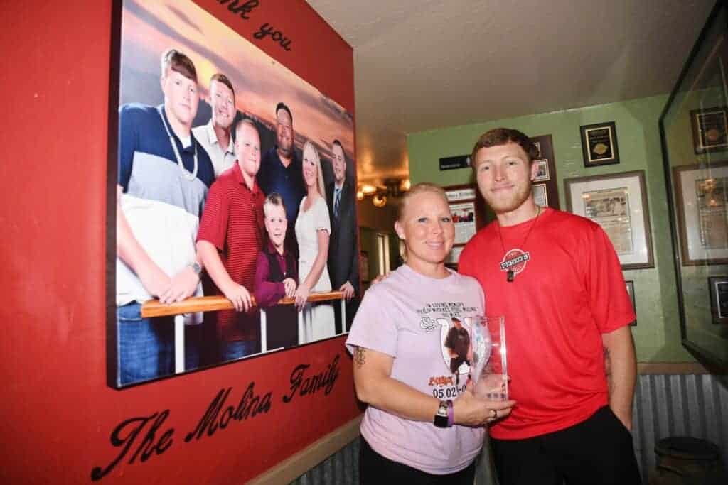 Photo - Madera’s Perko’s Cafe and Grill owner Kelly Molina holds the Heritage Award handed out by the Perko’s franchise for an owner that shows integrity, character and leadership. With Molina is her son Chris as they stand by a family picture on the wall at Perko’s.