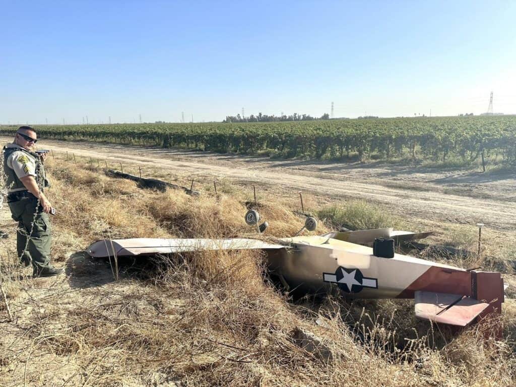 Photo - A Madera County Sheriff’s deputy stands near an experimental plane that crashed in Madera County on Thursday. The pilot was able to remove himself from the plane without incident.
