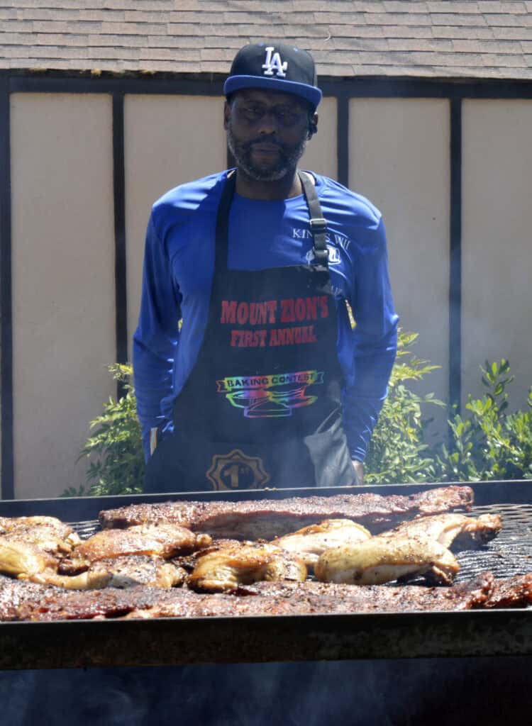 Photo - Sam Neely III grills pork ribs, chicken and tri-tip for visitors to try at the cook off.