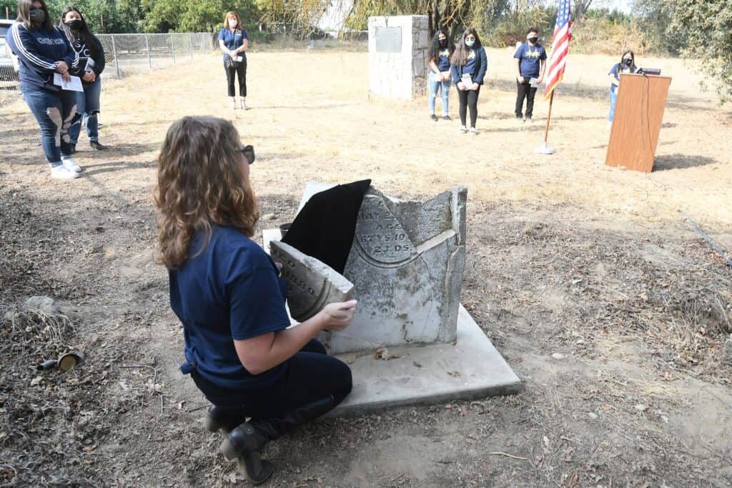 Photo - Dixieland School teacher Angela Lindsey puts a piece of a broken headstone in place at the grave of a former slave, Gabriel Bibbard Moore, during a ceremony on Nov 2.