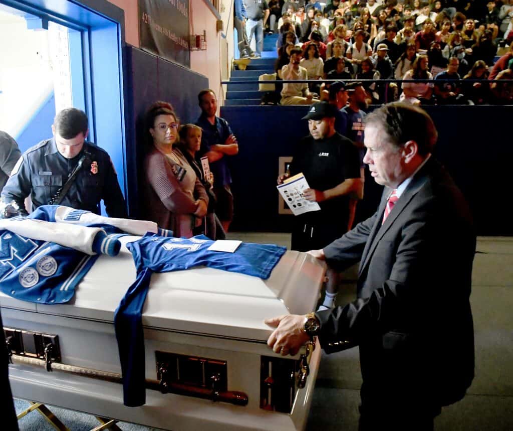 Photo - Jay Chapel funeral director Mark Peruch guides in the casket of Madera High student Isabel Jimenez for a reenacted funeral at the gym on Friday as part of the “Every 15 Minutes” program following a simulated car crash the day before.