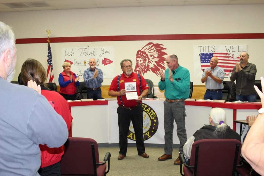 Photo - With Chowchilla High School trustees in the background, board president Pat DeWall leads the audience in a standing ovation for Royal Goodman who received his high school diploma Monday, 48 years after he left school to fight in Vietnam.