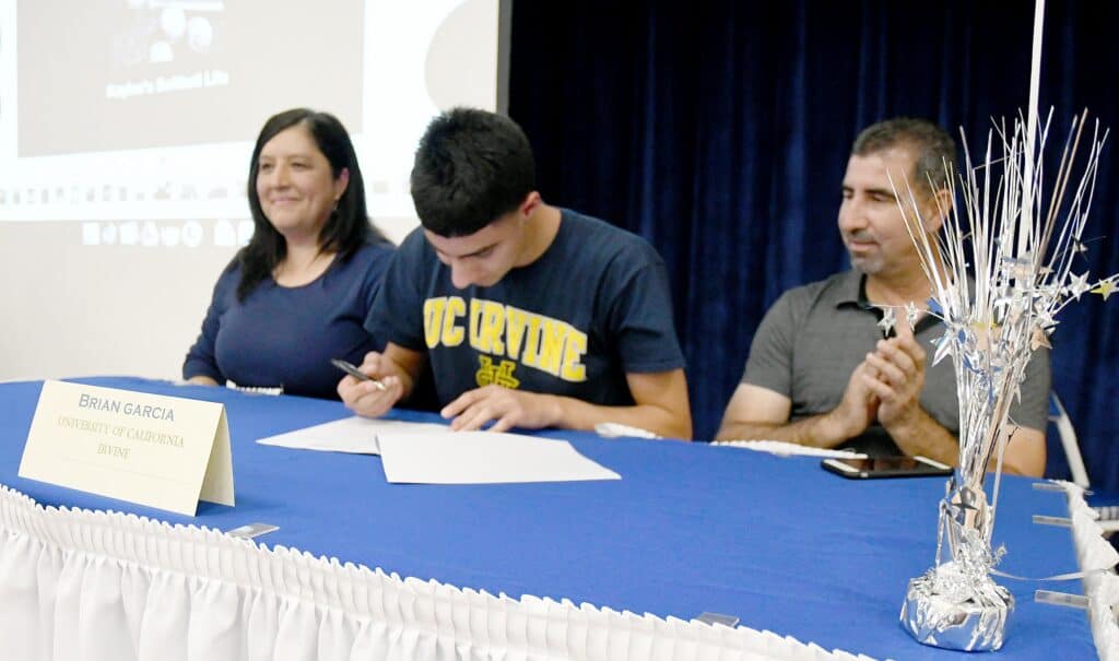 Photo - Madera Coyote volleyball player Brian Garcia signs his National Letter of Intent on Nov. 10 to UC Irvine while his parents Amparo and Robert Garcia look on.
