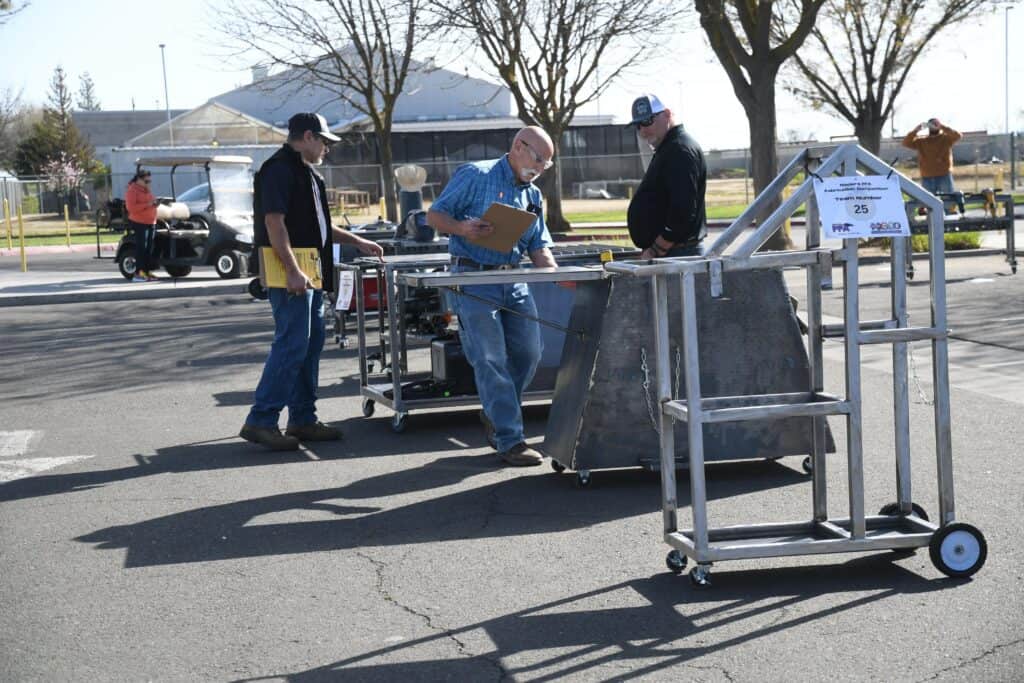 Photo - Judges look at a variety of carts that made it to the top 10 for further judging during an FFA fabrication competition.