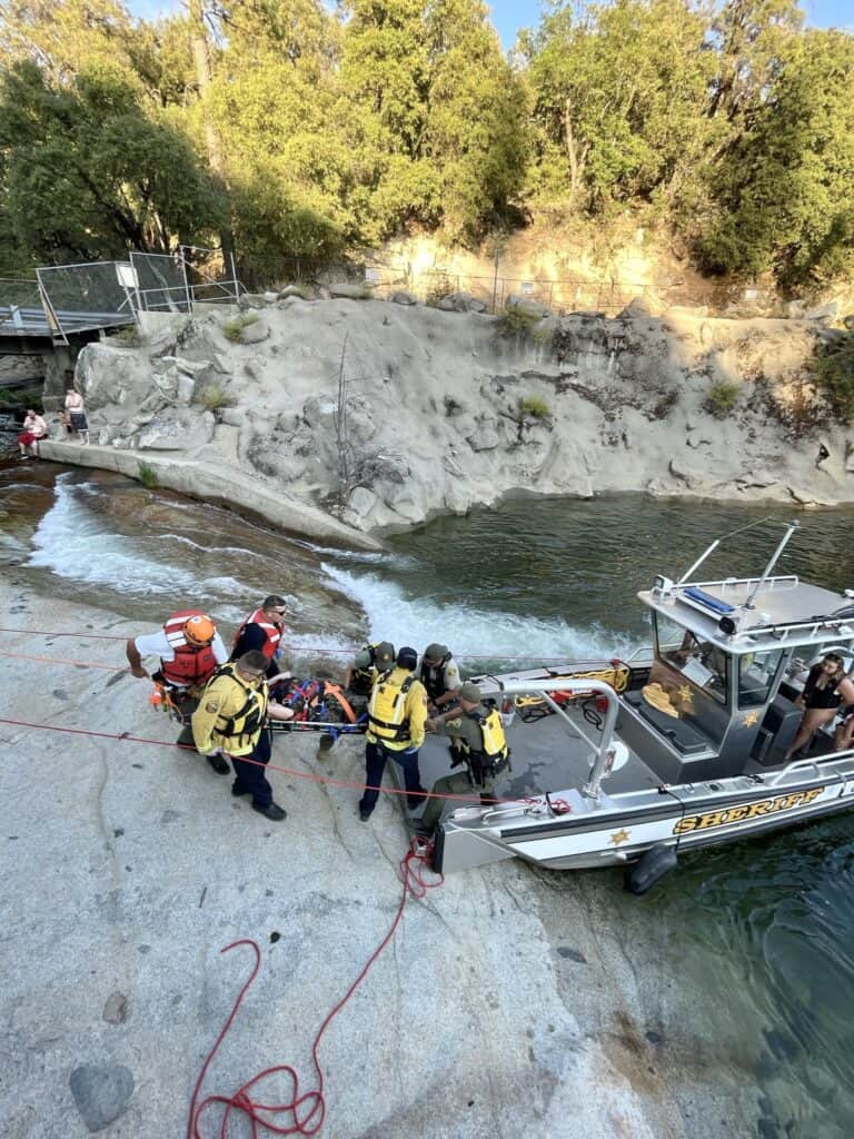 Photo - Madera County Sheriff’s Office Search and Rescue team help a female victim off the rocks at the Falls at Bass lake last week.