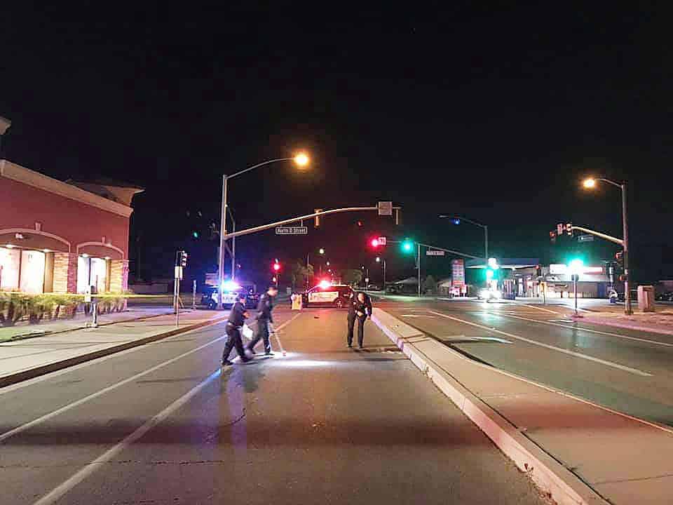 Photo - Officers look for evidence and vehicle parts after a unidentified man was struck and killed on Cleveland Avenue and D Street early Sunday morning. The man was reportedly in the crosswalk and was thrown about 130 feet to his death.