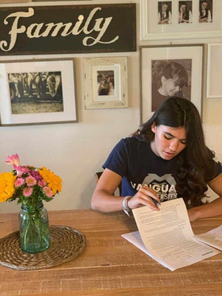 Photo - Madera’s Penelopi Leach looks over her paperwork before signing her National Letter of Intent to run the hurdles for the Vanguard University track team.