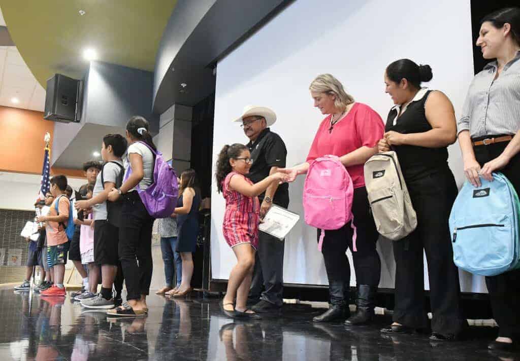 Photo - Valley State Prison representatives give backpacks to migrant ed students at Rose Elementary School on August 30, during Madera Unified School District’s Migrant Back to School Night.