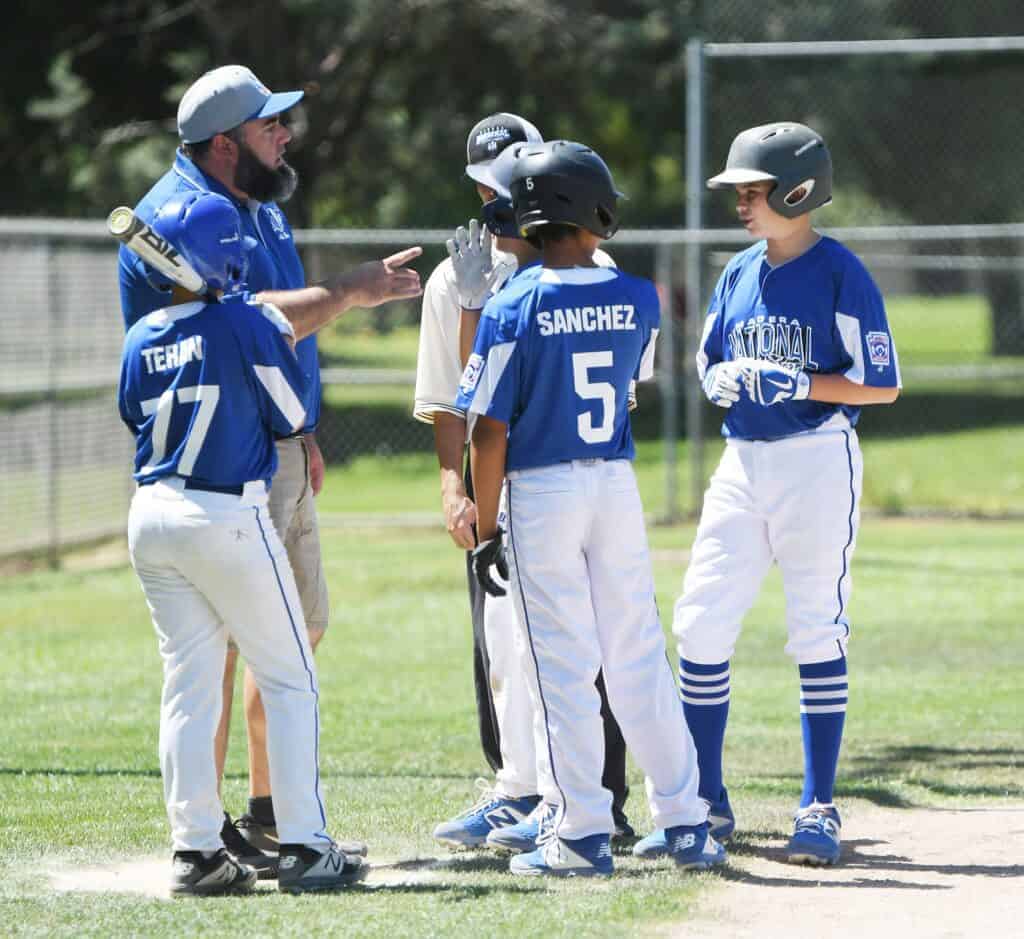 Photo - Madera National third base coach Seth McKeever holds a conference with Trevor Teran (77), Isaiah Sanchez (5) and Paul Stroemer.