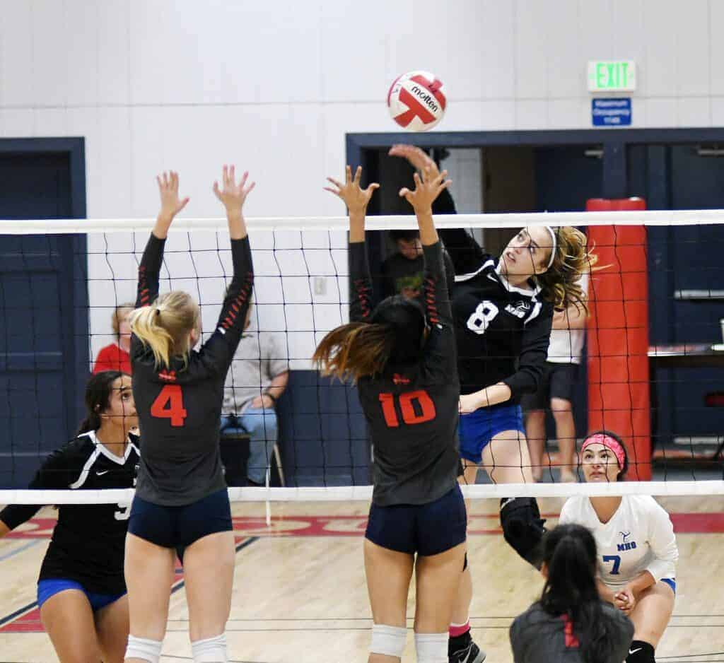 Photo - Madera middle blocker Hallie Page sends a kill past the San Joaquin Memorial blockers during Tuesday’s three-set victory over the Panthers.