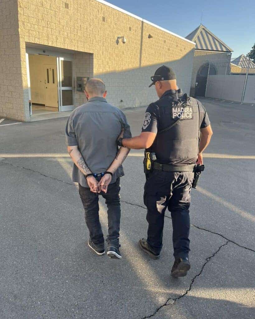 Photo - Kyle Cevasco is escorted into Madera Police Department custody after being arrested Friday night for several weapons-related charges.