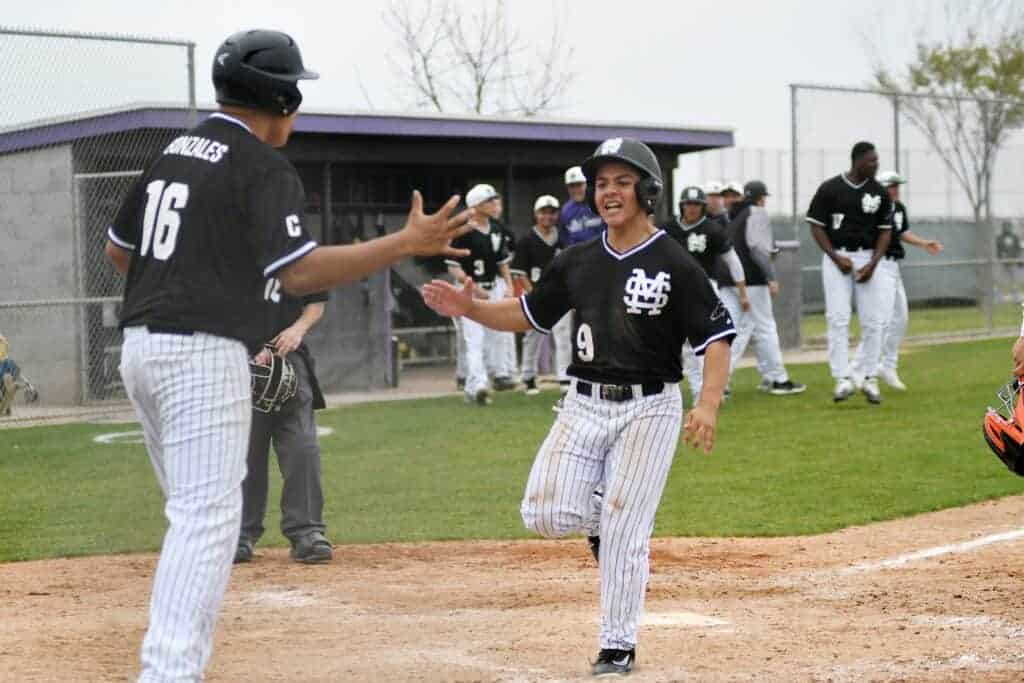 Photo - Madera South’s Carlos Gonzales, left, congratulates Jeremy Flores who scored the game-winning run Saturday against Selma.