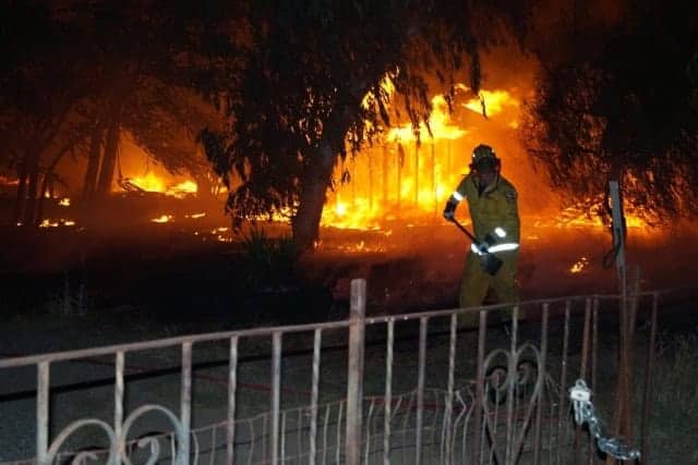 Photo - A firefighter battles a wind driven grass fire about 11:30 Saturday night off of Owens Street just north of Sherwood Way.