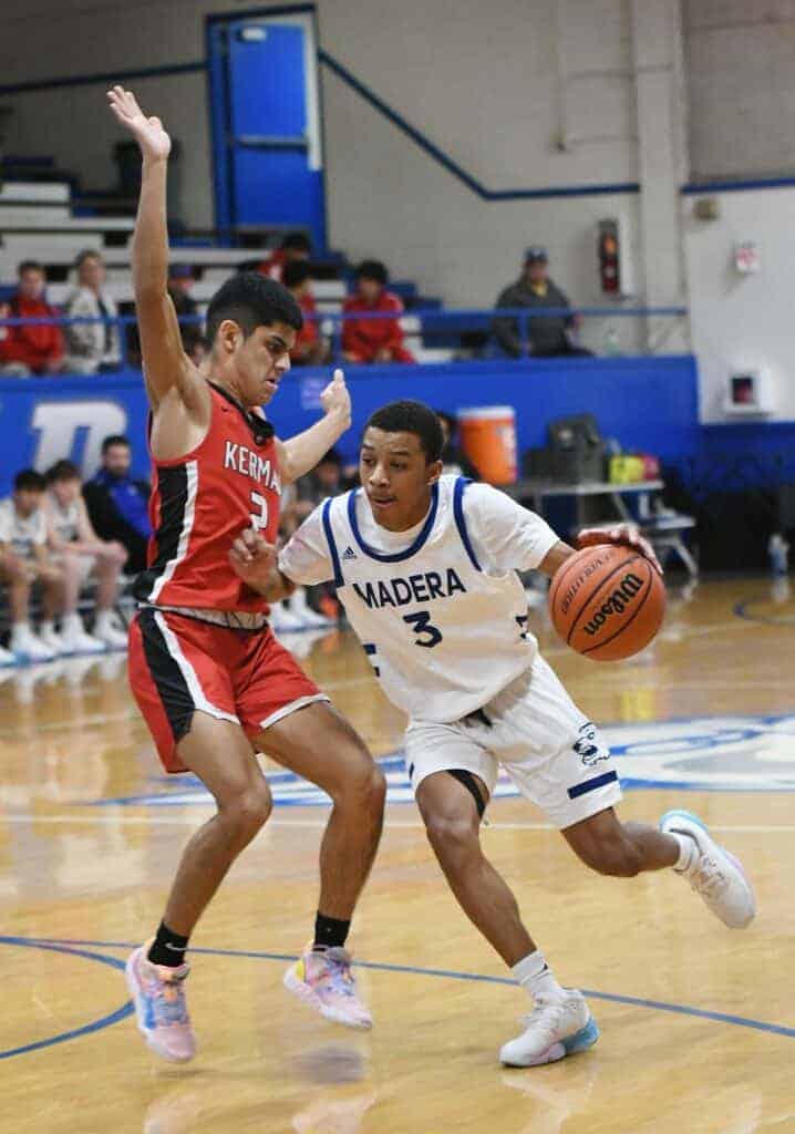 Photo - Madera guard JoJo Pickens tries to drive around a Kerman defender during Tuesday’s loss. Pickens led the Coyotes with 13 points.