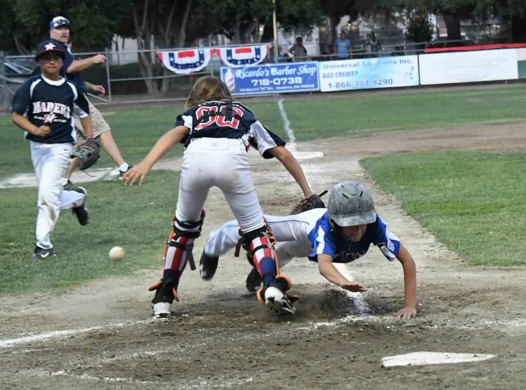Photo - Madera National’s Eric Nelson dives or the plate while Madera American catcher Malachi Watson looks for bal during Wednesday’s victory.