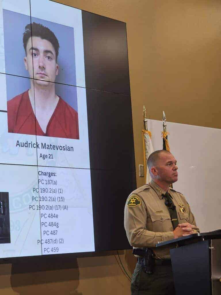 Photo - Madera County Sheriff Tyson Pogue speaks at a press conference to announce the murder of Robert Boyajian, and the apprehension of suspect Audrick Matevosian (in photo over shoulder) Thursday afternoon.