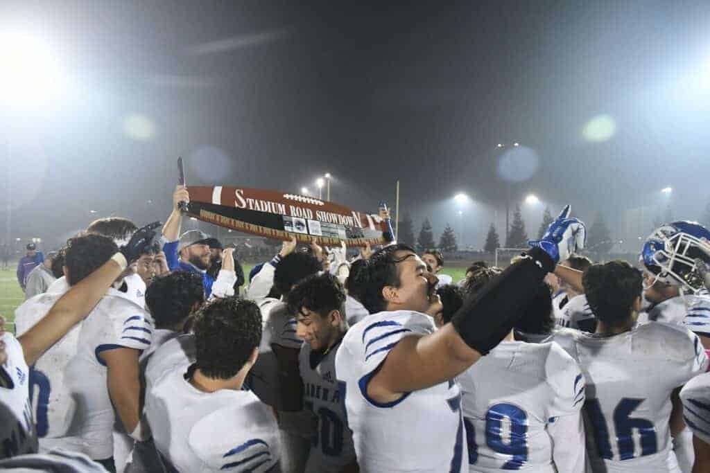 Photo - Madera Coyotes football coach Kenny Paolinelli presents the Stadium Road Showdown Saw trophy to his team after a 37-20 victory Friday in Memorial Stadium.