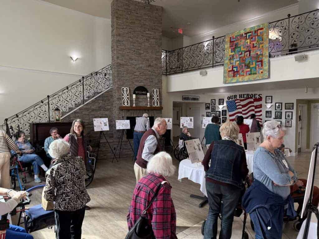 Photo - Guests and residents at Cedar Creek Senior Living gather in the lobby to view biographies of the women who live in the facility in honor of Women’s History Month on March 28.