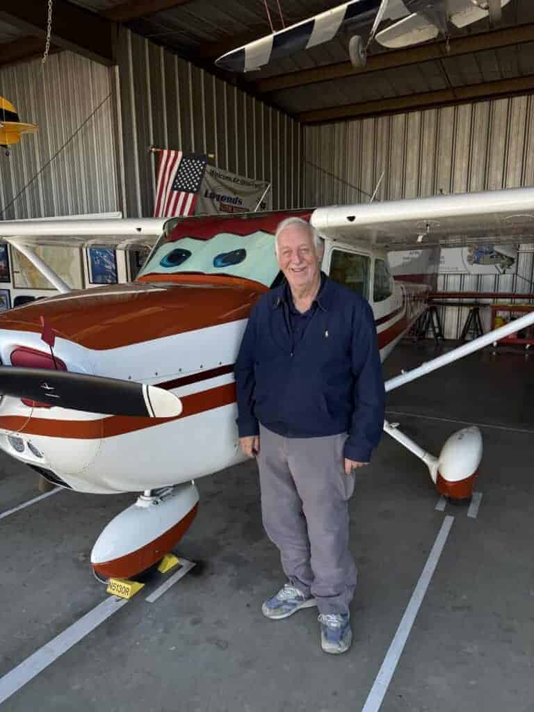 Photo - Pilot Jim Shamp stands under his airplane which displays eyes like the characters of the movie, “Planes,” which he had a part in. Shamp has been flying for more than six decades.