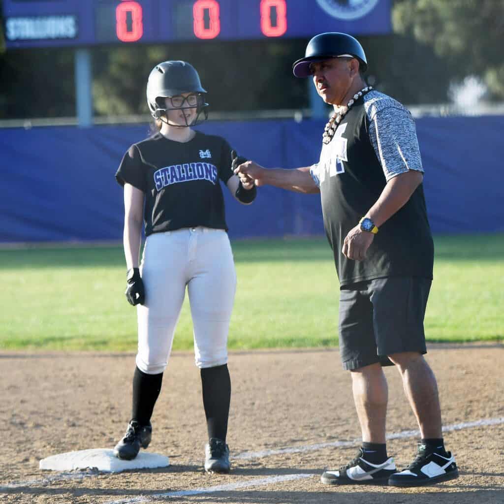 Photo - Madera South coach Alfonso Cuevas gives a fist bump to Alejandra Bermudez after she reached on an error in the fourth inning of Monday’s non-conference loss to Livingston.