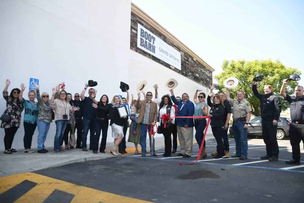 Photo - Boot Barn store manager, Westin Conriguez, is joined by family, friends, community leaders and dignitaries for a ribbon-cutting ceremony and grand opening Friday for the new store on Cleveland Ave.