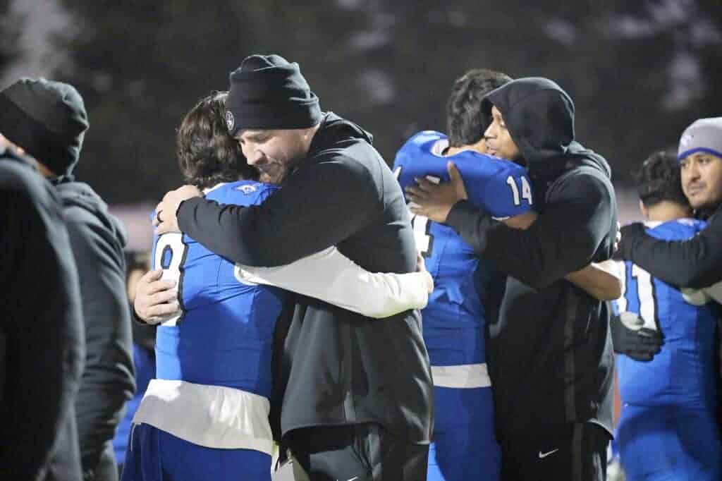 Photo - Madera Coyote football coach Kenny Paolinelli gives senior quarterback Joel Arellano a hug after Friday’s Div. III Championship game loss to Kerman.