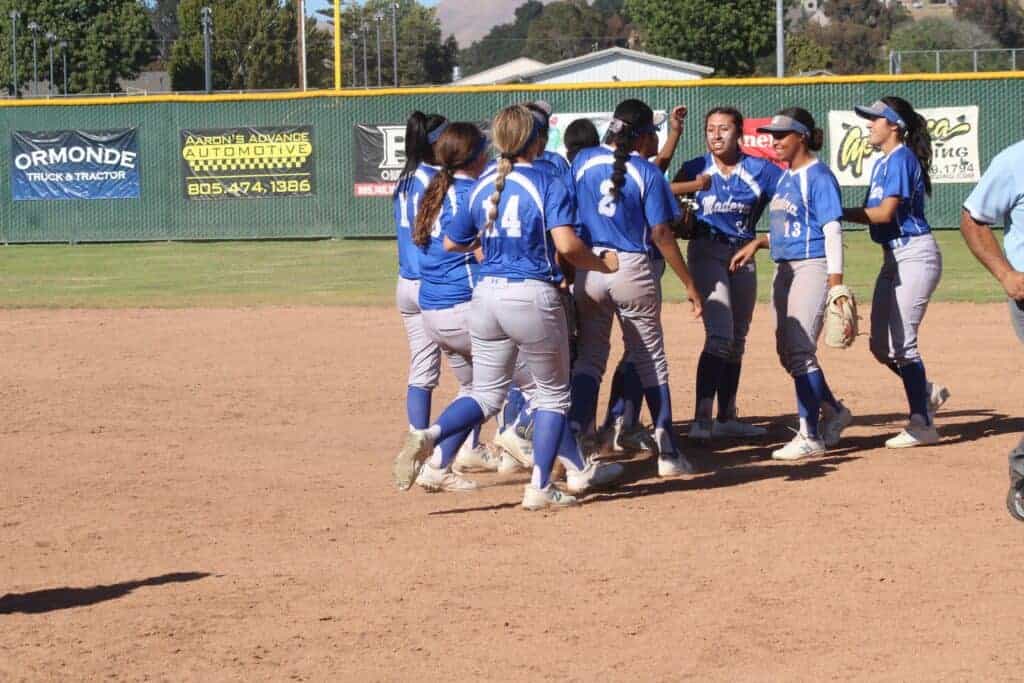 Photo - The Madera Coyotes softball team gathers around Alexis Galvan (facing front) after she picked up a 3-2 victory over Arroyo Grande in the circle Tuesday.