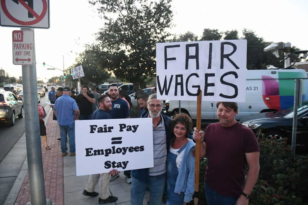 Photo - Protestors hold signs in front of the Madera City Hall Wednesday night asking for what they called fair wages and bargaining in good faith.
