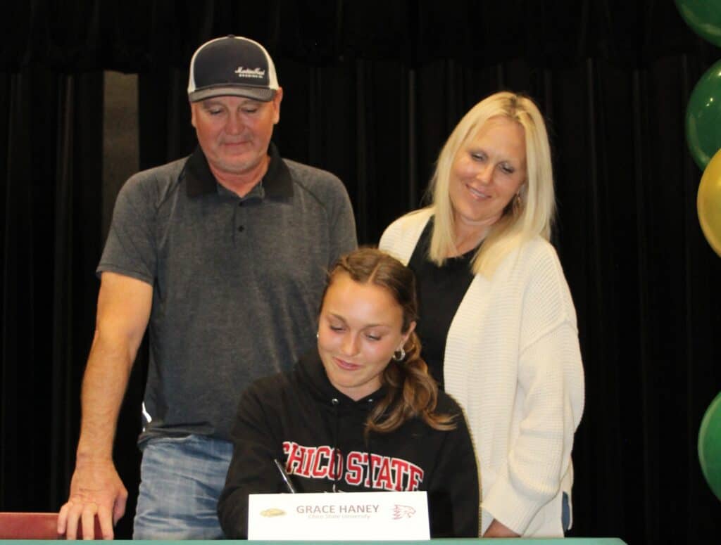 Photo - Liberty track star Grace Haney officially signs her National Letter of Intent with her parents watching at a Liberty singing event in May. Haney was one of five Liberty athletes, and one of two track athletes, to sign to a four-year college.