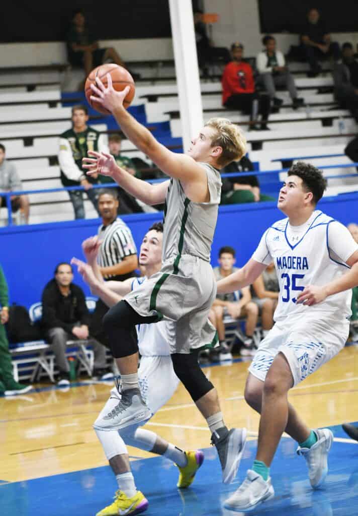 Photo - Liberty’s Logan Stephens drives to the hoop in front of Madera’s Sammy Hass to score two of his team-high 15 points in Tuesday’s 58-52 victory.
