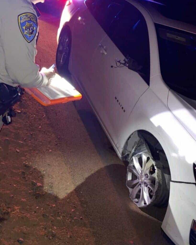 Photo - A CHP Madera officer writes up a citation for the driver of this white Chevrolet Malibu which was seen driving without a front right tire and riding on the rim.