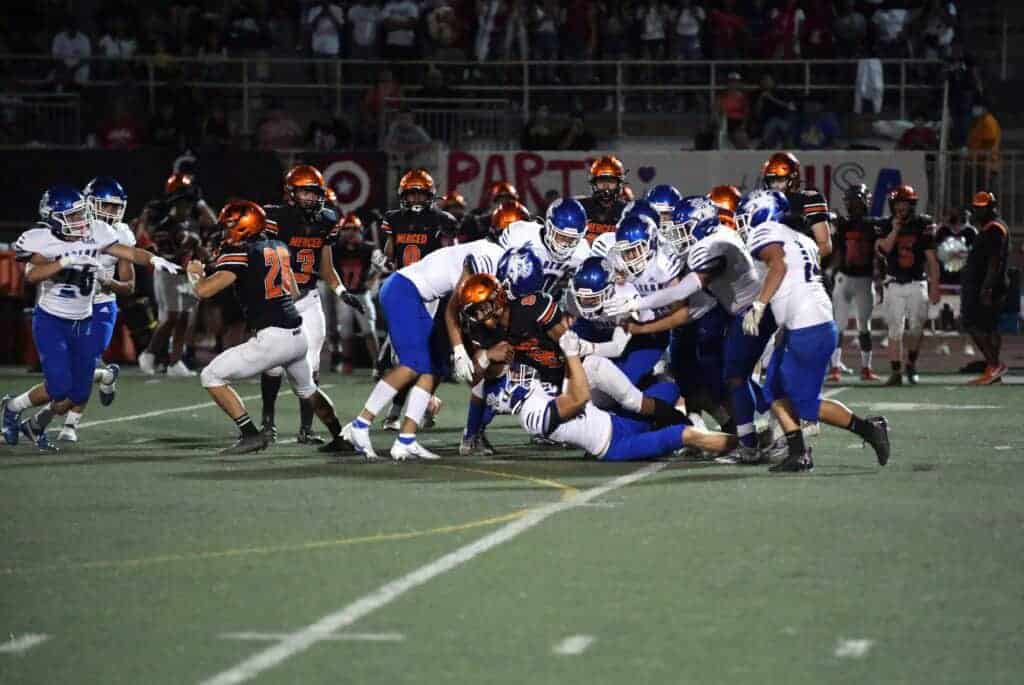 Photo - The Madera Coyotes defense stuff a Merced runner during Thursday’s loss to the Bears.