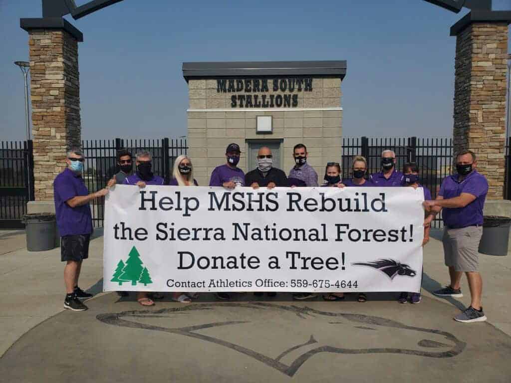Photo - Madera South High School staff hold a banner to announce their drive to help replant the Sierra National Forest with a sapling drive.