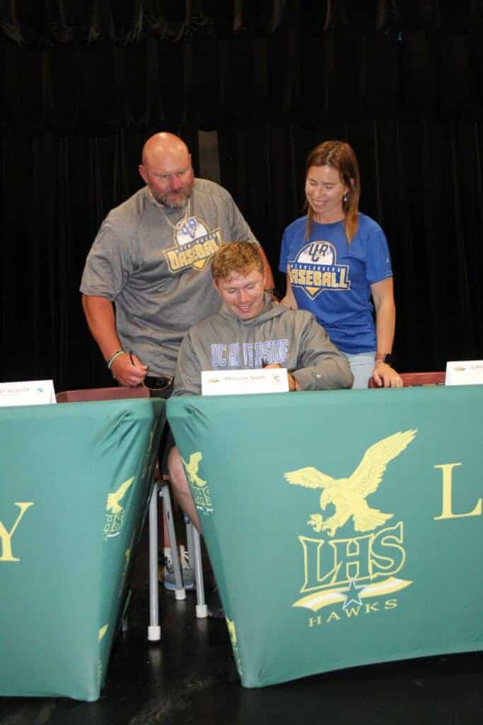 Photo - Liberty baseball standout McGuire Smith signs his National Letter of Intent with his parents watching at a Liberty High School signing day in May. 
