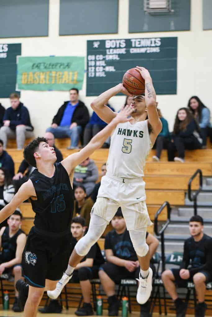 Photo - Liberty’s Makani Whiteside gets a shot off despite a hand in his face. He scored a game-high 25 points in a Div. V first round victory.