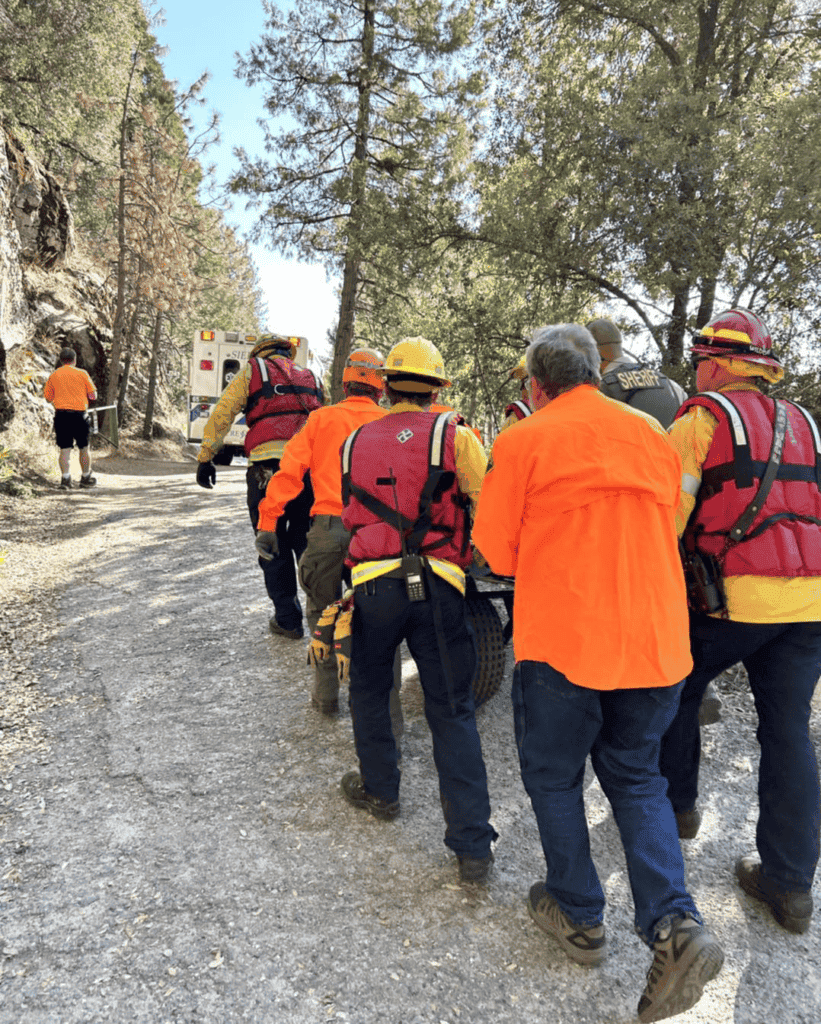 Photo - An injured hiker that broke her ankle diving into Bass Lake is transported out of the area to an awaiting ambulance by Madera County Sheriff’s Search and Rescue team members.