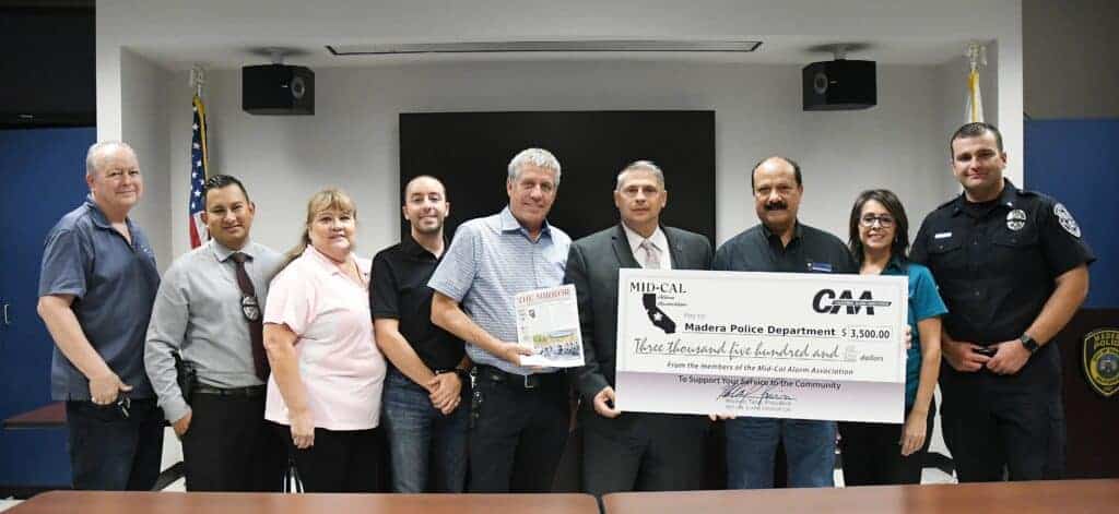 Photo - Recieving a check for $3,500 to the Madera Police Department, from the Mid-Cal Alarm Association from left, Steve Cockrum, Det. John Rosel Jr., Gloria Molina, Garrett Teran, Mike Matson, Chief Dino Lawson, Michael Teran, Conner Teran and Lt. Brian Esteves.