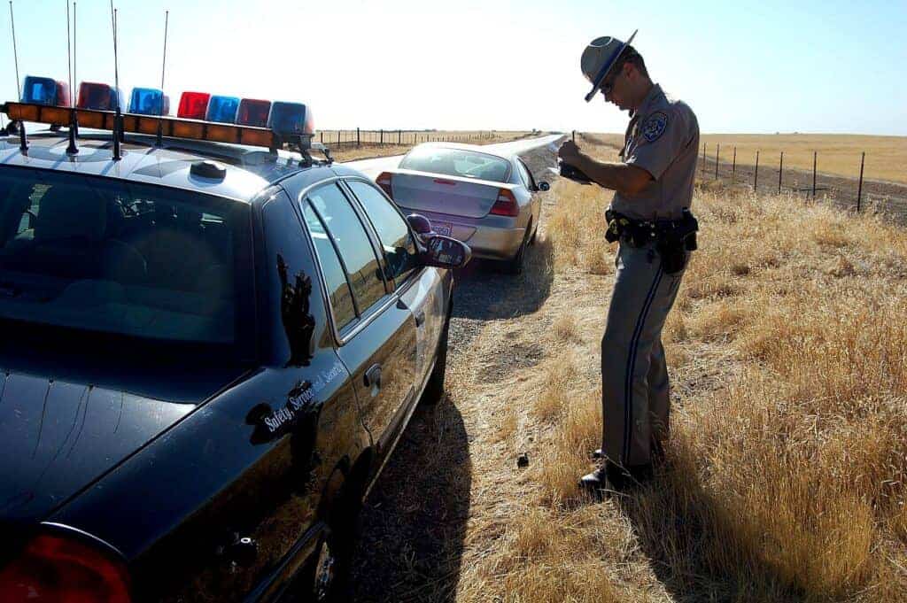 Photo - A California Highway Patrol officer writes out a speeding ticket after pulling over a driver along Avenue 15 in Madera.