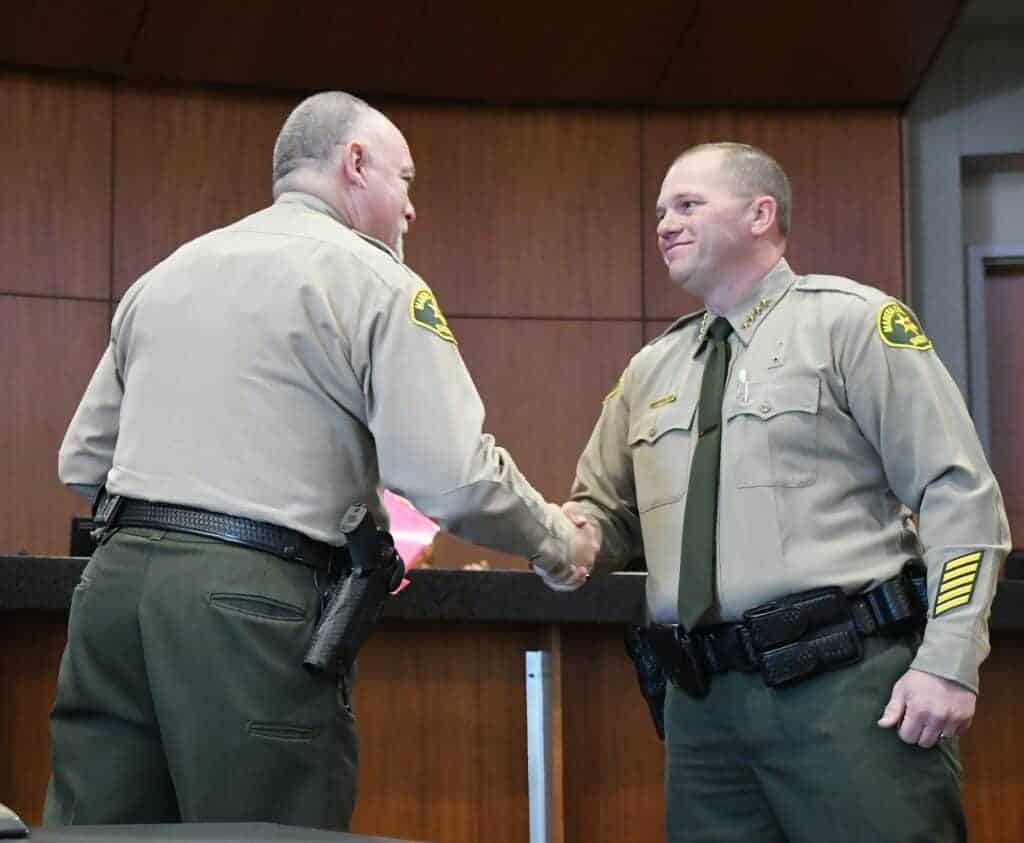 Photo - Former Madera County Sheriff Jay Varney, left, congratulates newly appointed Sheriff Tyson Pogue after Varney administered the oath of office during the Madera County Board of Supervisors meeting on June 16.