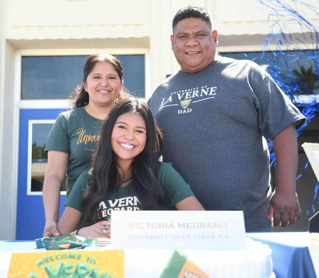 Photo - Madera’s Victoria Medrano is surrounded by her parents after signing her National Letter of Intent to run cross country and track at the University of La Verne.