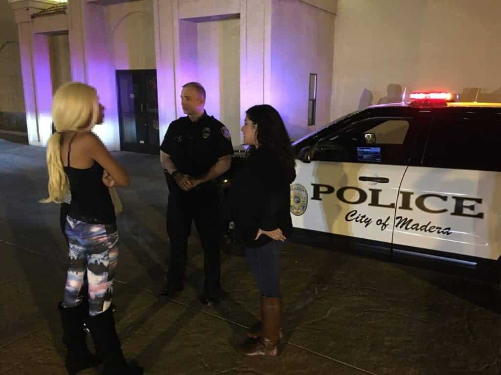Photo - An unidentified woman, left, suspected of being sexually trafficked, is contacted by Madera Police officer Scott Roberts and a female police volunteer last year. The young woman was offered options out of a life of working on the streets.