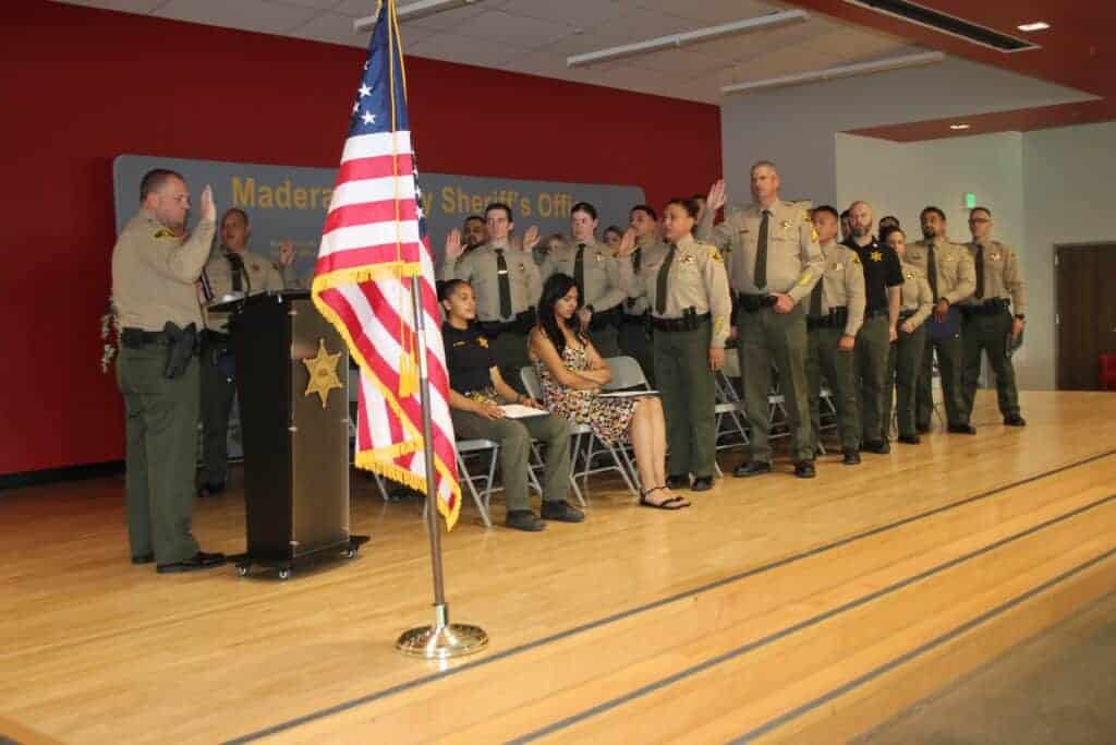 Photo - Madera County Sheriff Tyson Pogue reads the Oath of Office to six recently promoted employees and 22 new hires to the Madera County Sheriff’s Office during a Swearing-in, Promotions and Awards Ceremony at Matilda Torres High School on June 15.