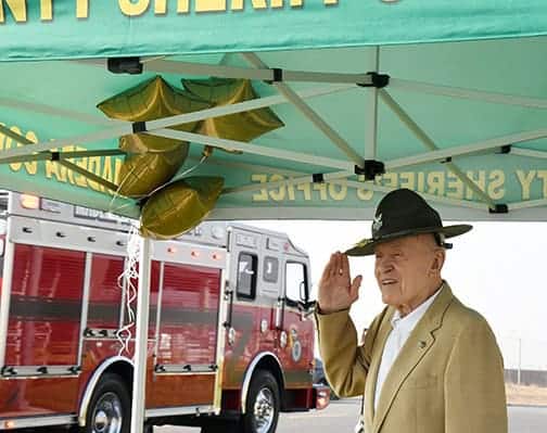 Photo - Retired Madera County Sheriff Ed Bates salutes a parade of local law enforcement represetatives, first responders and others participating in a parade honoring Bates on his 95th birthday Tuesday in front of the Madera County Sheriff’s Department.